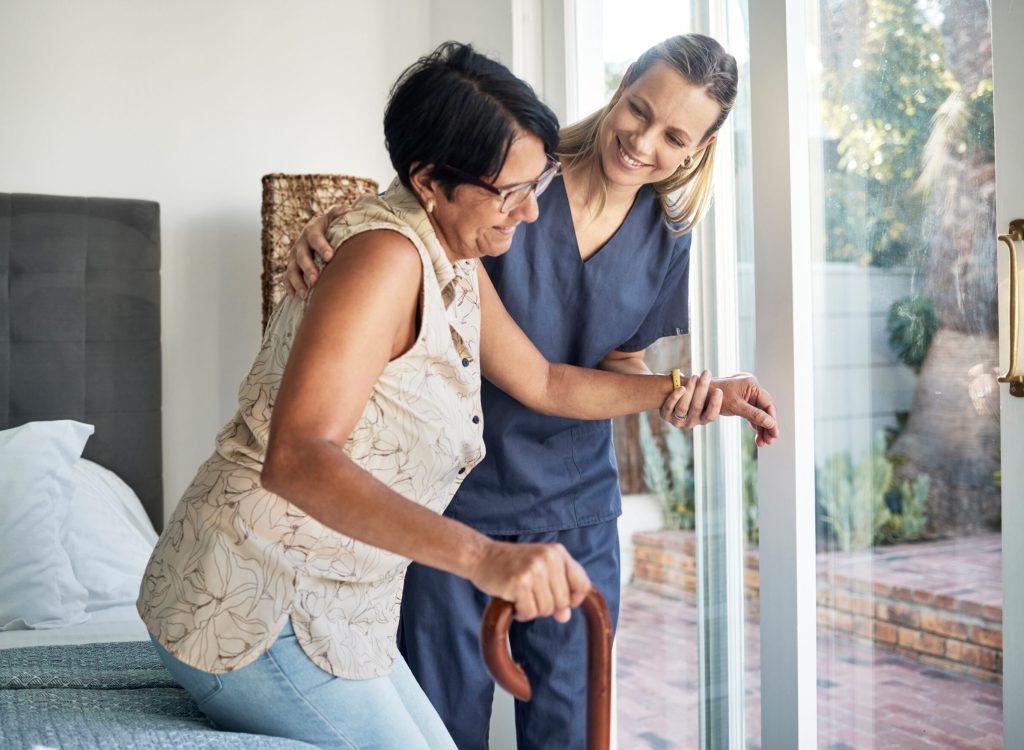 Happy woman, nurse and senior in elderly care, support or walking with stick at old age home. Medical caregiver or therapist helping patient or person with a disability in retirement or physiotherapy.